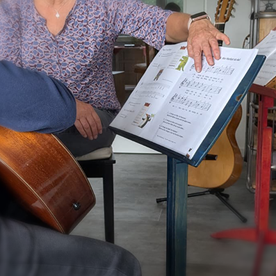 die Gitarrenlehrerin zeigt im Unterricht auf Notenblätter